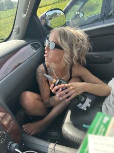 Woman in a car inhaling nitrous oxide from a tank.
