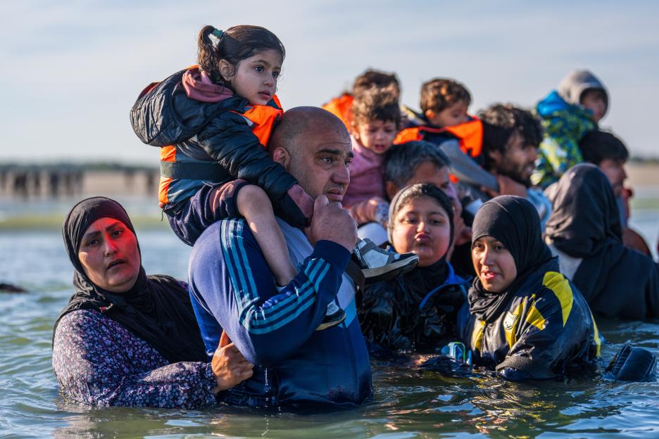 Refugees wading into the sea.