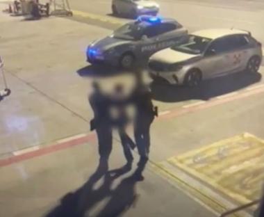 Police officers escorting disruptive passengers from a plane at an airport.