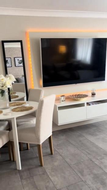A dining area with a large TV mounted on the wall above a white media console.