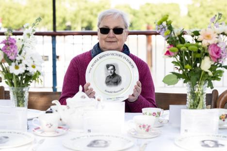 Woman holding commemorative plate of WWII hero Arnold Sharrocks.