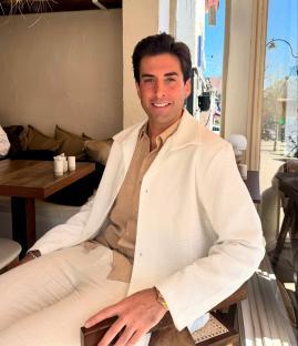 Man in white jacket sitting at a restaurant table.