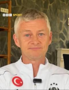 A man in a white jacket speaks.
