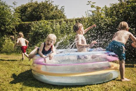 Four children playing in a paddling pool.