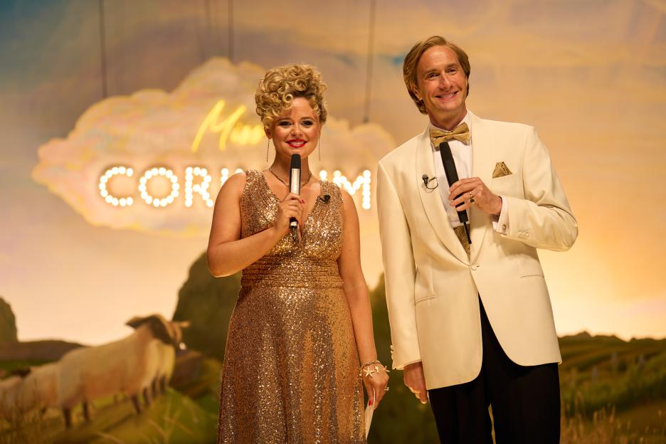 Still from *Rivals* episode 5 on Disney+, showing two hosts on stage.