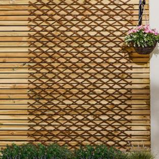 Brown expanding willow trellis on a wooden fence.