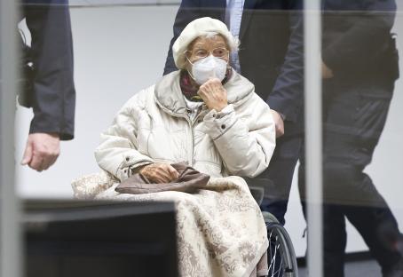 an elderly woman wearing a mask sits in a wheelchair