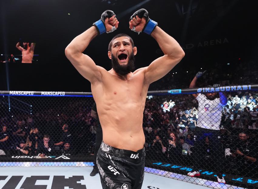 a man in a ufc ring with his arms in the air