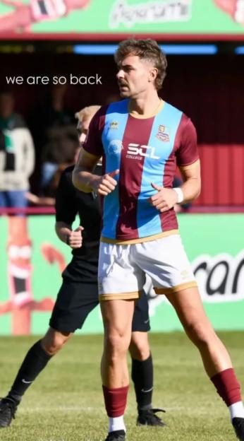 Football player in a maroon and light blue striped jersey, white shorts, and maroon socks on a field.