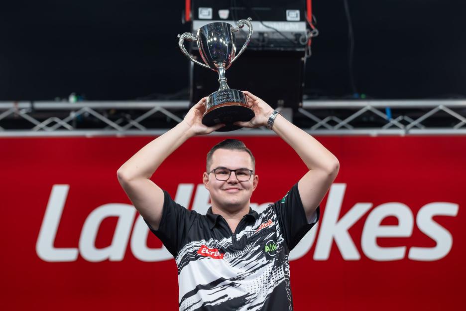 Gian van Veen holding the Winmau World Youth Championship trophy.