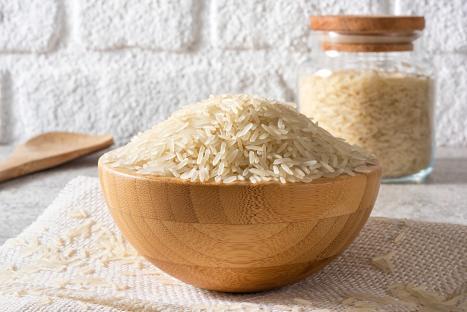 A wooden bowl of uncooked jasmine rice.