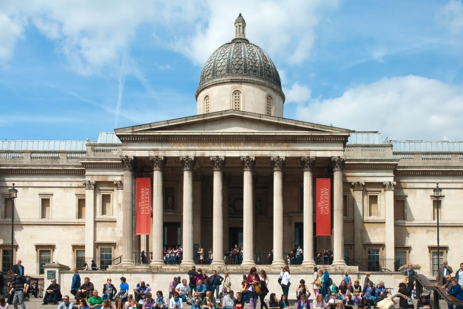 The National Gallery in London, with a red banner stating "The National Gallery" hanging from the building and many people gathered on the steps below.