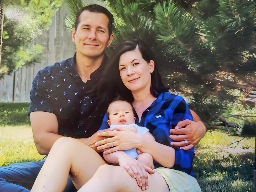 A family portrait of a man, woman, and baby.