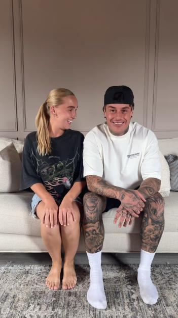 Couple sitting on a couch, smiling at each other.
