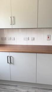 DIY kitchen makeover with light grey cabinets and wood countertop.