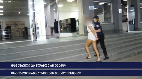 A young woman in handcuffs being escorted by a police officer.