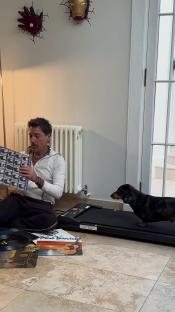 Man looking at vinyl records with his dachshund on a treadmill.