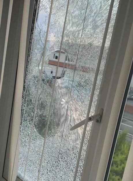 Shattered window glass with a hole in the center.