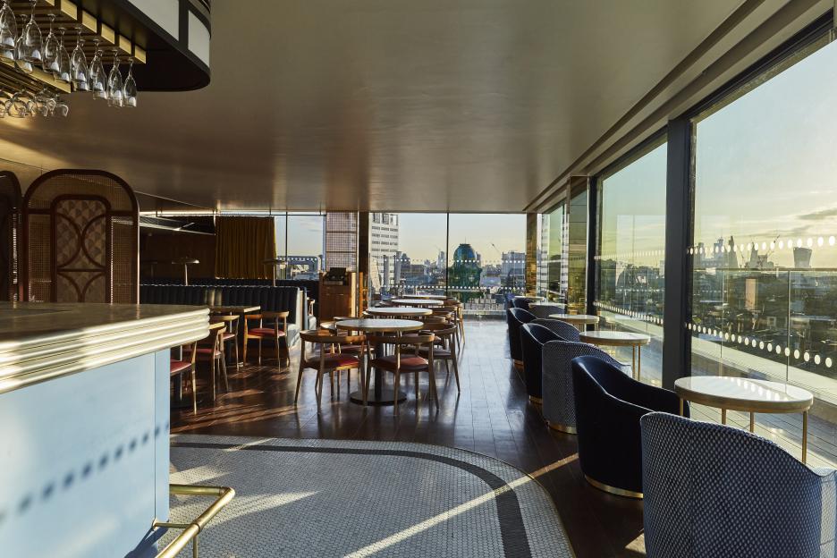 A hotel lounge and bar with a cityscape view from large windows.