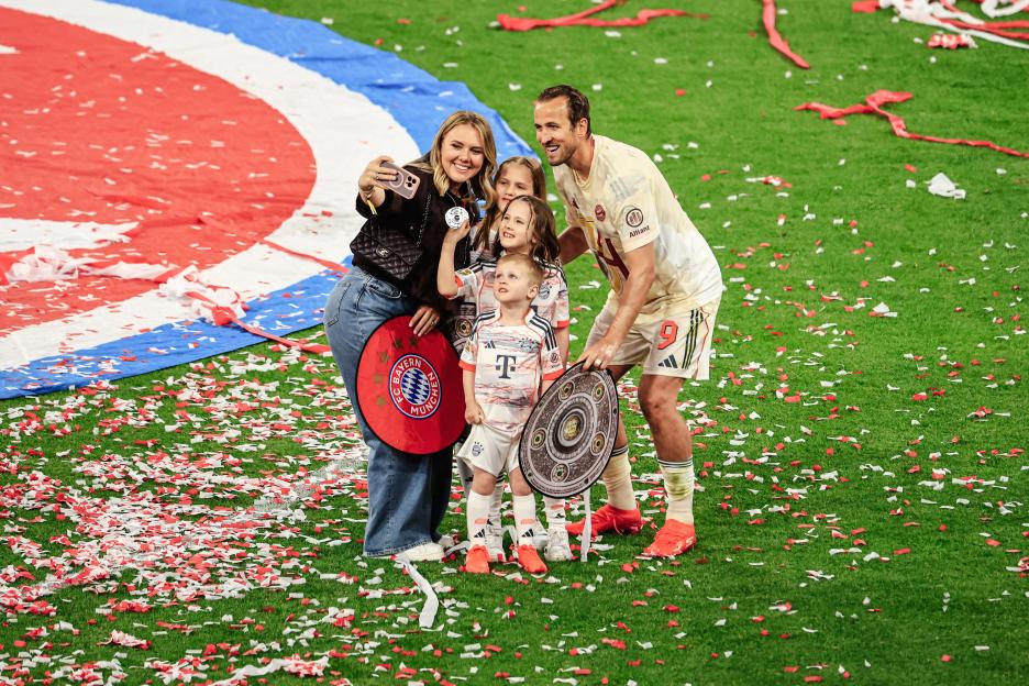 Harry Kane of Bayern München with his family taking a selfie on the field after a game.
