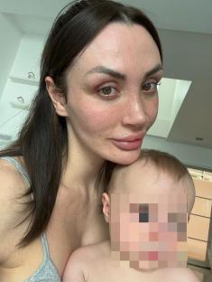 Woman holding a baby; baby's face is pixelated.