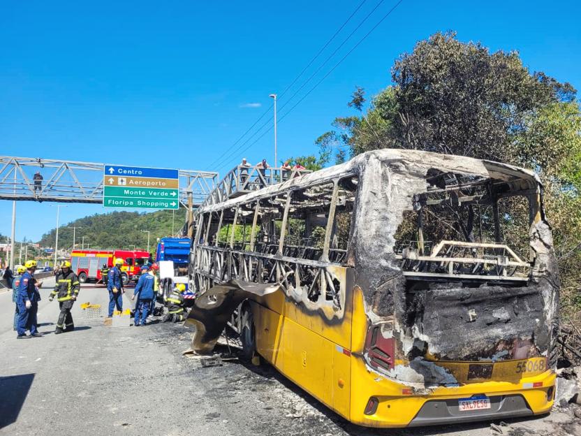 Burnt-out yellow bus on the side of a road after a collision.