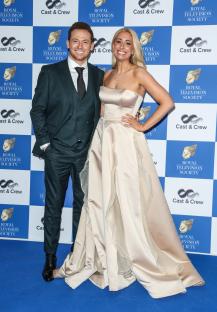 a man and a woman pose for a picture in front of a wall that says royal television society