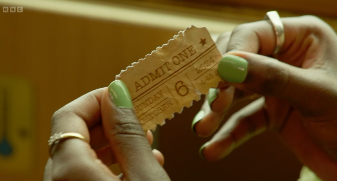 Hands holding a torn admission ticket.