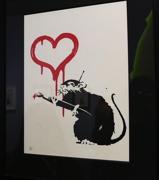 A woman viewing Banksy's "Love Rat" screenprint.
