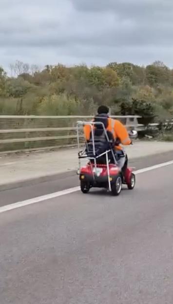 Dashcam footage of an elderly man on a mobility scooter riding down a busy motorway.