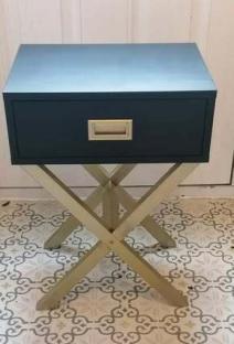 Dark blue bedside table with gold legs and drawer.