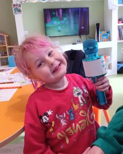 Girl with pink hair holding a microphone.