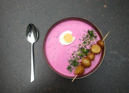 Bowl of pink beet soup with a hard-boiled egg and roasted potatoes.