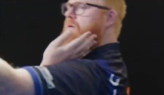 Red-haired man with glasses throwing darts.