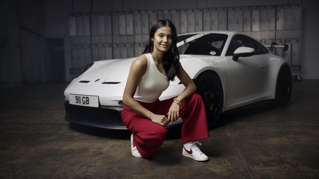 Emma Raducanu posing with a white Porsche.
