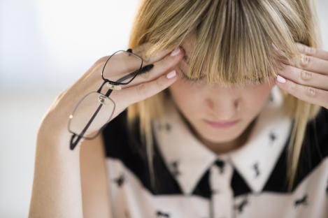Woman holding her head in her hands, looking stressed.