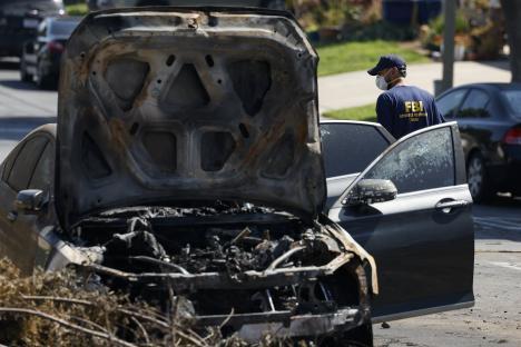 A burned-out car at an airplane crash site with an FBI agent investigating.