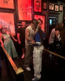 Couple embracing in a room with framed artwork.