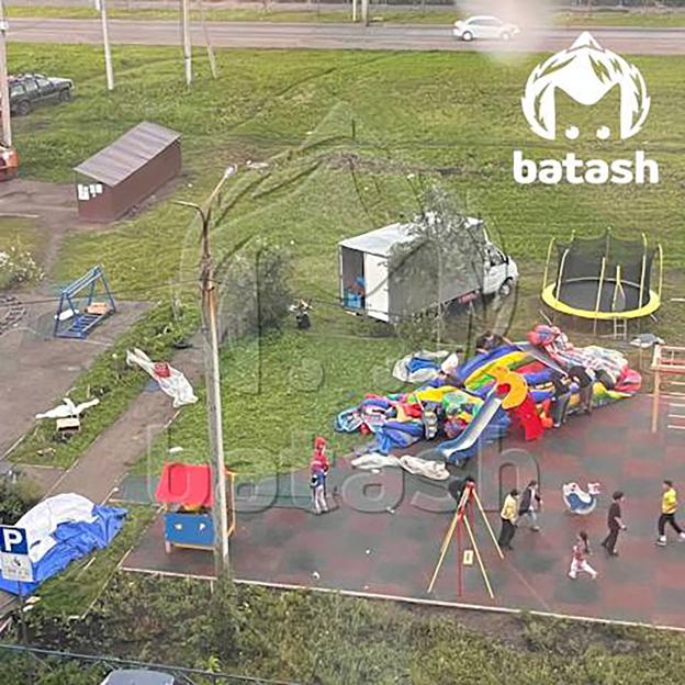A bouncy castle filled with children overturned in a playground.