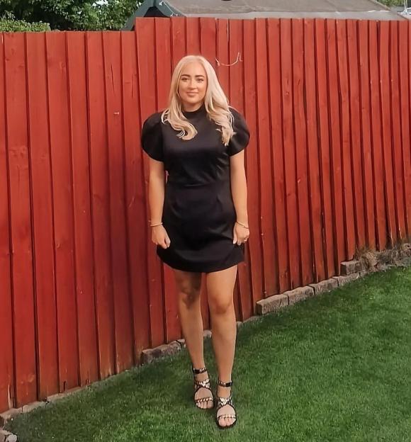 Woman in black dress in front of a red fence. Text overlay: "You will lose a shit load of weight!"