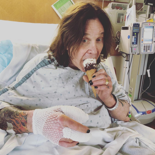 Man in hospital gown eating ice cream cone.
