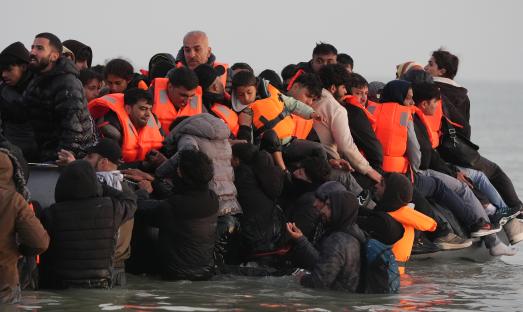 Migrants in life vests aboard a small boat in the water.