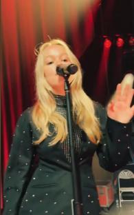 Jemma Donovan singing into a microphone on stage.