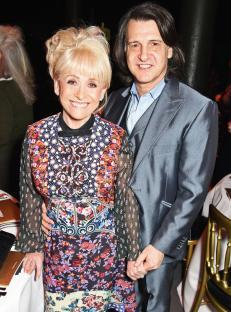 a woman in a floral dress stands next to a man in a suit