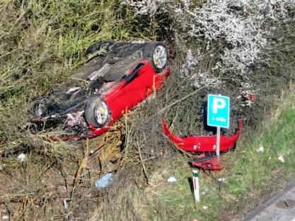 Wreckage of a red car in a bush.