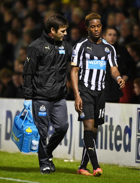 Newcastle's Rolando Aarons walks off the pitch with the physio after sustaining an injury.