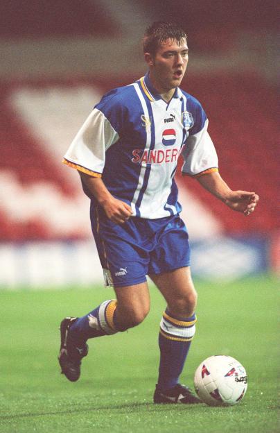 Soccer player in a blue and white uniform dribbling the ball.