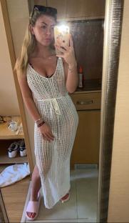Woman in a white crochet maxi dress taking a selfie.