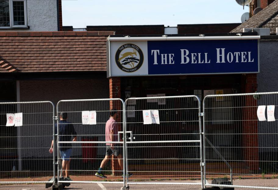 Men walking past a fenced-off Bell Hotel following a court injunction.