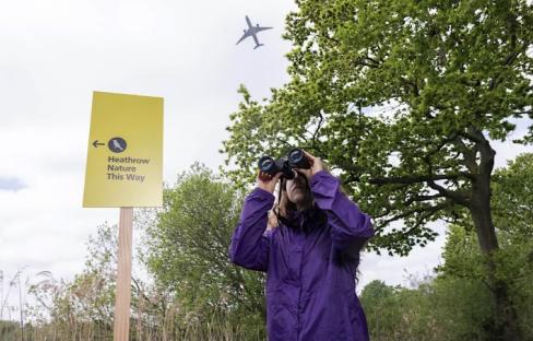 Woman using binoculars at Heathrow Nature Reserve.